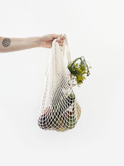 arm holding white string bag